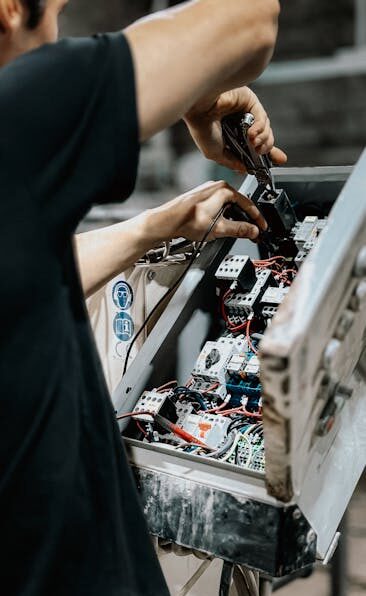 Technician adjusting wires in an electrical control panel for maintenance
